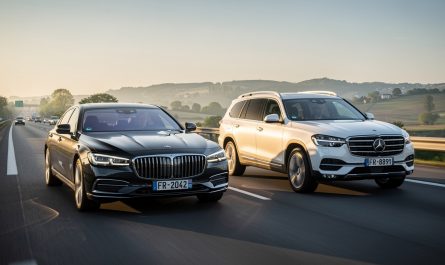 Une berline moderne et un SUV familial roulent côte à côte sur une autoroute française éclairée par une douce lumière matinale.